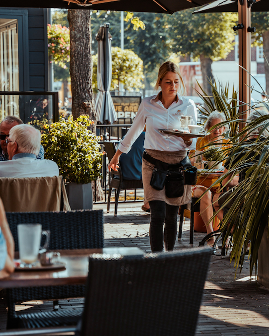 Foto in der Innenstadt von Uden, das einen Kellner zeigt, der Getränke bringt