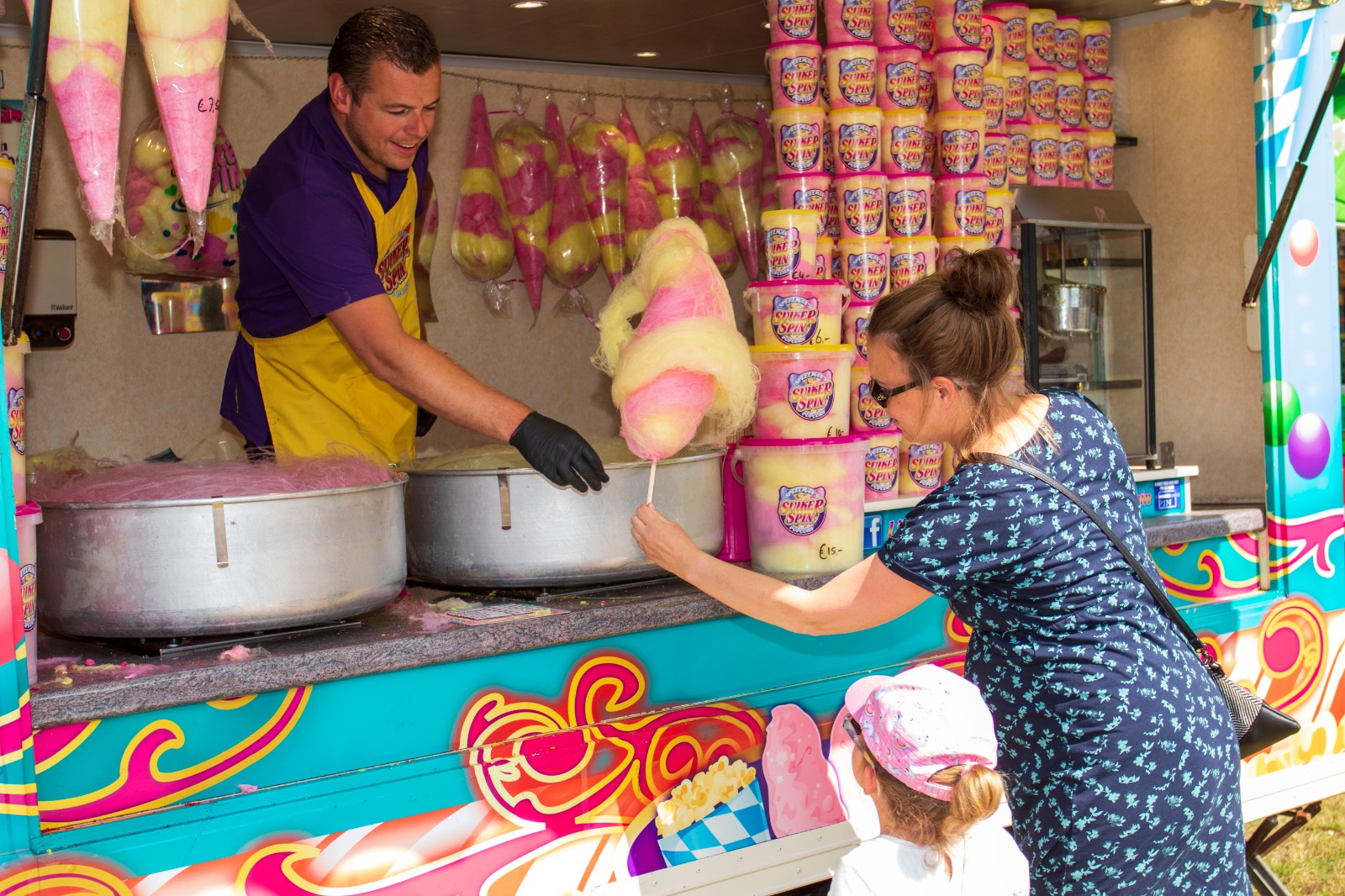 Suikerspin kraam waarbij suikerspin overhandigd wordt